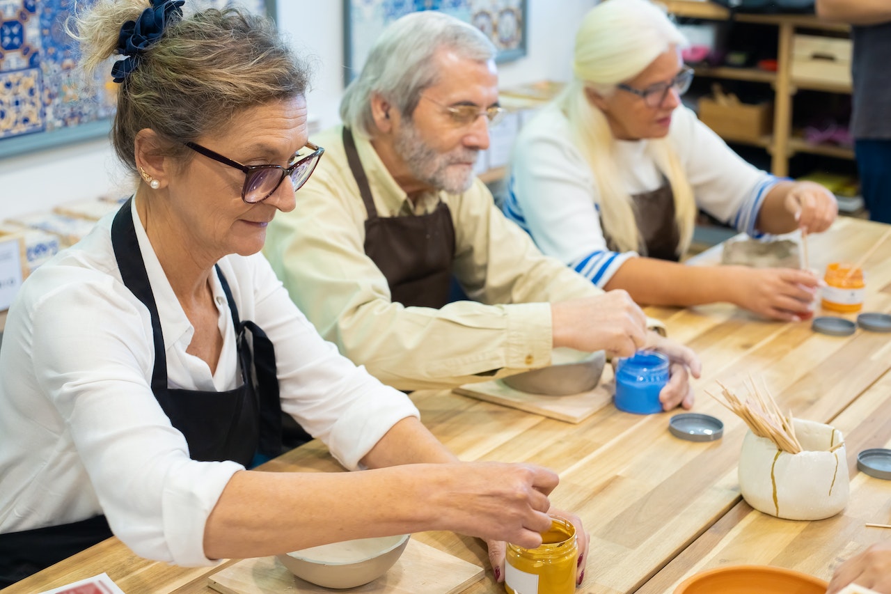 one elderly man and two elderly women enjoying art session in their retirement